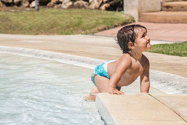 Baby girl crawling in the pool shore. stock photo