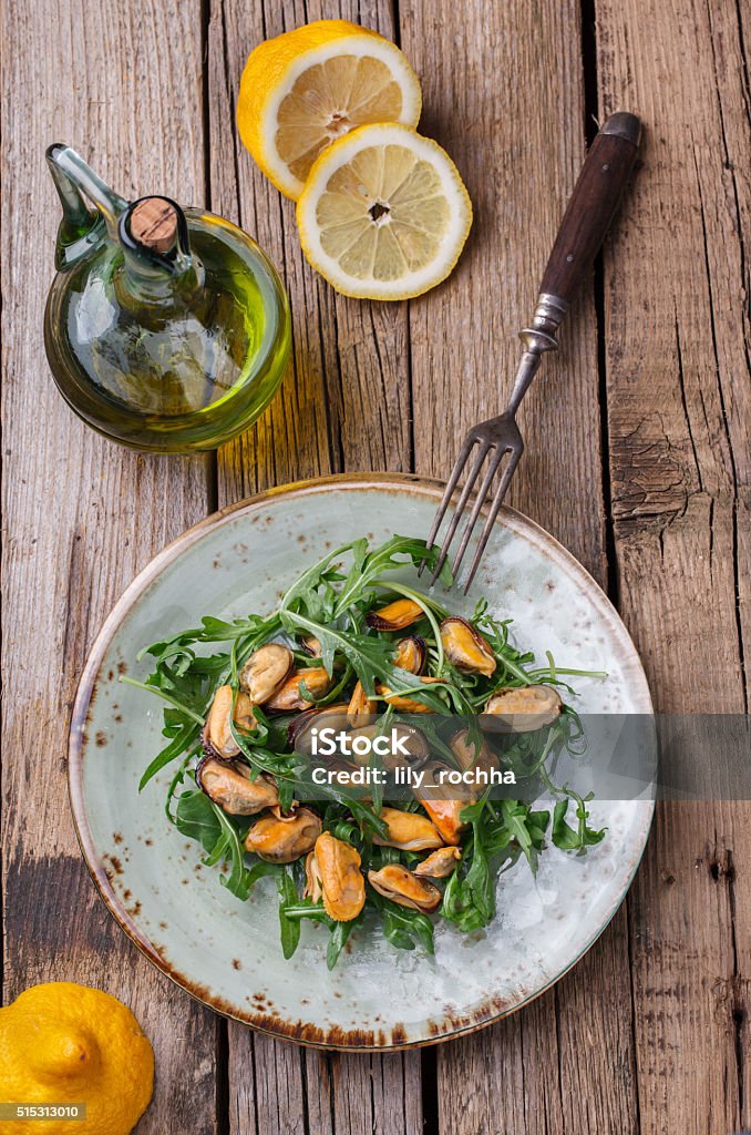 Salad with mussels and arugula Salad with mussels and arugula on a glass plate with olive oil and lemon.selective focus Appetizer Stock Photo