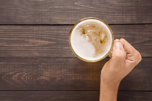 Hand is holding a glass of beer in the pub.