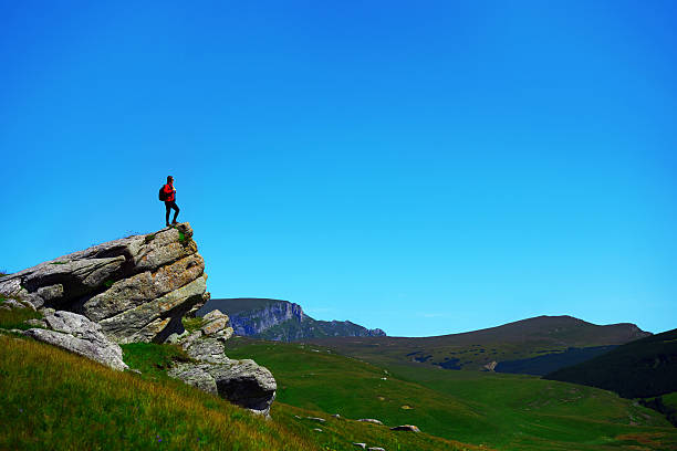 Man sitting on the edge of a cliff overlooking the mountains below