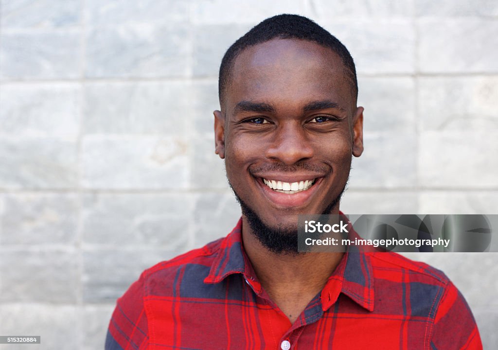 Happy young african man smiling against gray wall Close up portrait of happy young african man smiling against gray wall Portrait Stock Photo