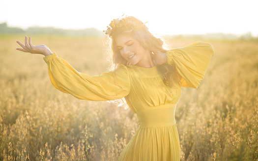 Happy young beautiful woman wearing flower garland in fields with tremendous sunlight flare.