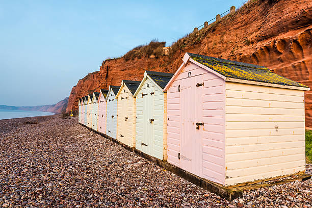 istock Beach hut row in pastel colors, red rock cliff background 515367718