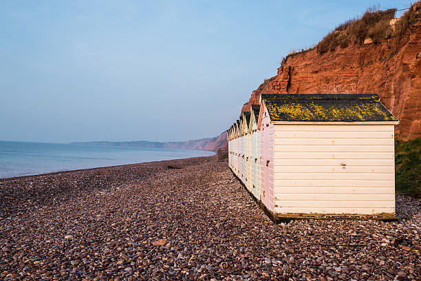 istock Beach hut row in pastel colors, red rock cliff background 515367934