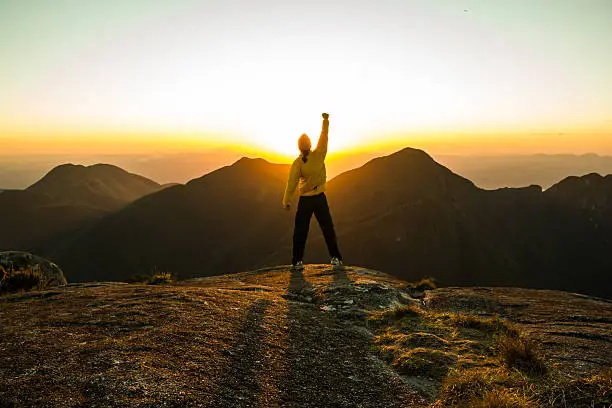 Photo of Man celebrating success on top of a mountain