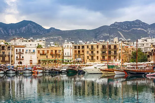 Photo of the waterfront and harbour with sailboats in Kyrenia, Northern Cyprus with mountains in the background.