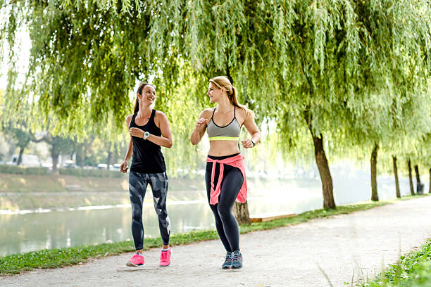 femmes rapidement à pied dans le parc - power walking photos et images de collection