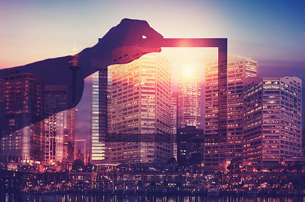 Business man holding a picture frame over city.