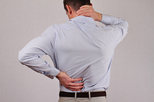 Man rubbing his painful back close up. Business man holding his lower back. Pain relief concept