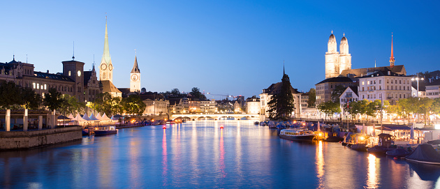 Panoramic view of the Fraumunster church (left) and Grossmünster church (right) in central Zurich on the Limmat river at twilight, Switzerland