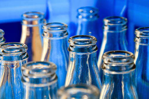 Empty glass bottles in a blue plastic crate.