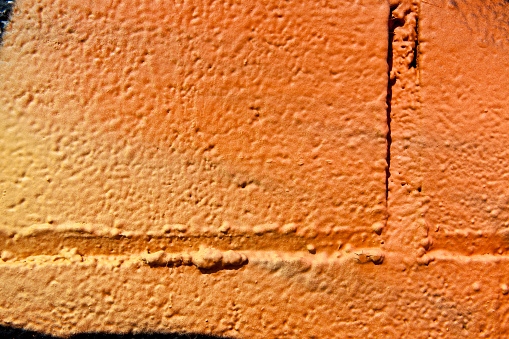 Orange and yellow paint on block wall, spray paint, Grafitti layer with many paint layers.