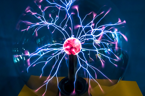 Plasma ball  with magenta-blue flames on the table and dark background