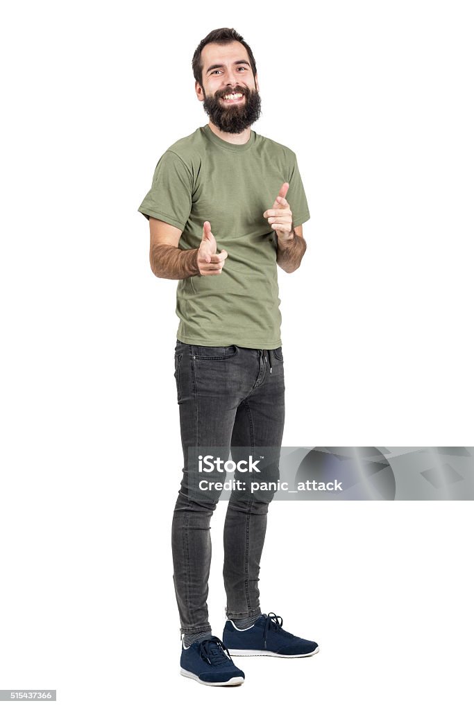Spontaneously laughing man in green t-shirt pointing fingers at camera Spontaneously laughing bearded man in green t-shirt pointing fingers at camera. Full body length portrait isolated over white studio background Men Stock Photo
