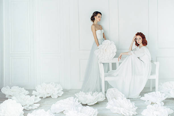 Studio shot of two young beautiful brides on background of flowers. Professional make-up and hairstyle.