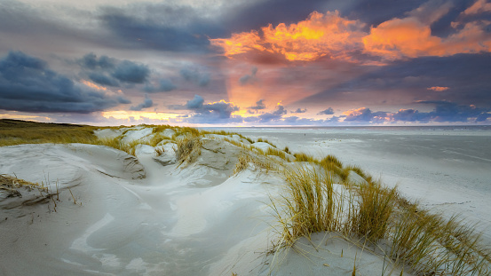 Sunset on the island of Texel with dunes and dune grass with a wide beach below.