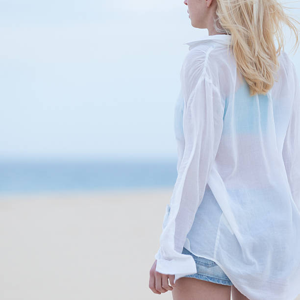 istock Woman on sandy beach in white shirt at dusk. 515441236