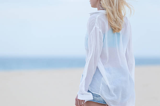 istock Woman on sandy beach in white shirt at dusk. 515441406