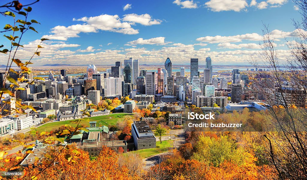 Autumn Colors in Montreal City A Mountain view of Montreal City, Canada in the fall.  The sky is clear and it is a sunny day.  A cluster of gray, multiple-sized buildings are visible in the center of the photo.  Lush, fall foliage lines the front of the image, and a body of water is visible in the back of the photo. Montréal Stock Photo