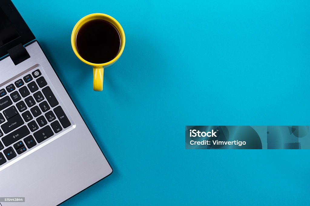 Office table desk with set of colorful supplies, white blank Office table desk with set of colorful supplies, white blank note pad, cup, pen, pc, crumpled paper, flower on blue background. Top view and copy space for text. Desk Stock Photo