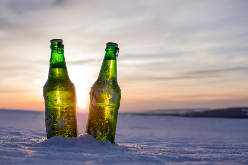 Two bottles of cold beer at sunset