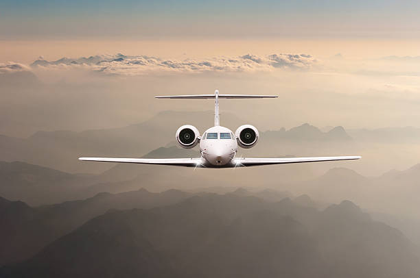 Airplane fly over clouds and Alps mountain on sunset. Front Airplane fly over clouds and Alps mountain on sunset. Front view of a big passenger or cargo aircraft, business jet, airline. Transportation and travel concept. military private stock pictures, royalty-free photos & images