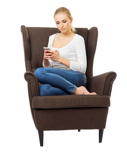 istock Young girl with mobile phone on chair 515452341