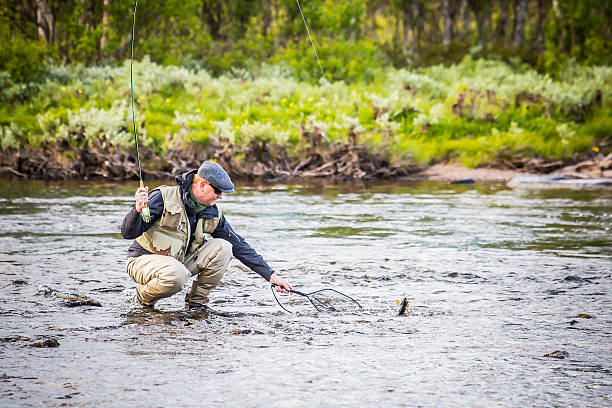 istock Fly fisherman in grey cap and vest catching a grayling 515455795