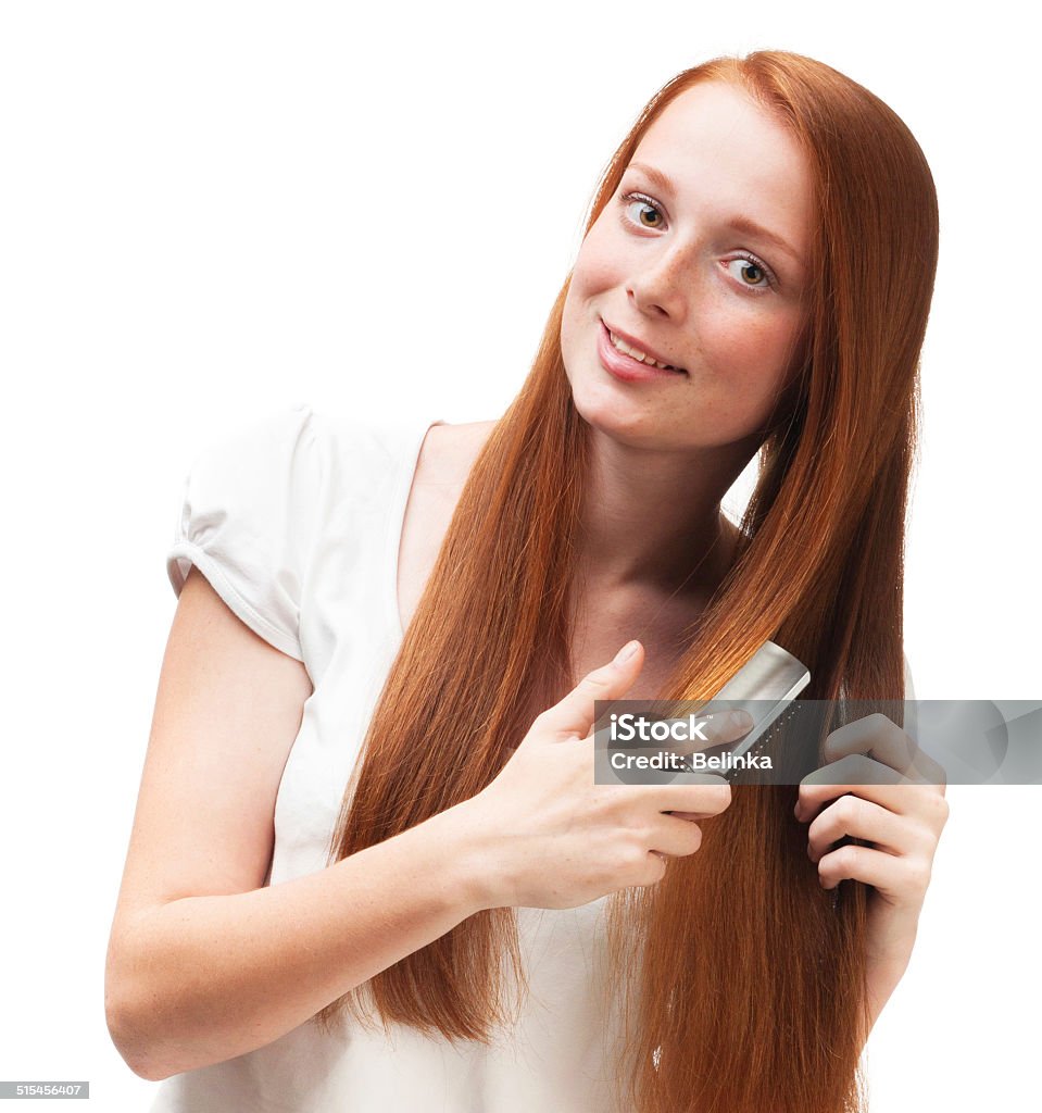 Young red-haired girl combing her long hair. Young red-haired girl combing her long hair. Isolated on white background Adult Stock Photo