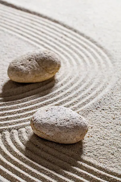 zen sand still-life - stones set on sinuous lines for concept of change or separation with inner peace