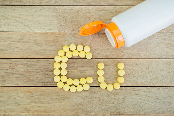 istock Yellow pills forming shape to Cu alphabet on wood background 515475034