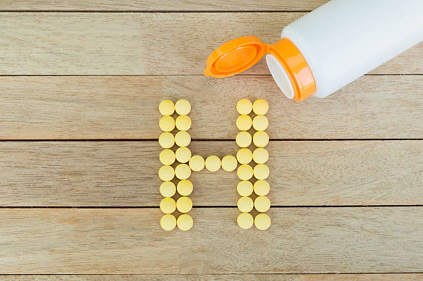 istock Yellow pills forming shape to H alphabet on wood background 515475288