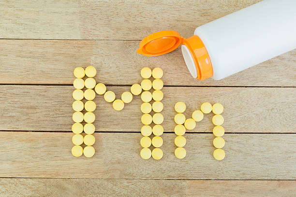 istock Yellow pills forming shape to Mn alphabet on wood background 515475746