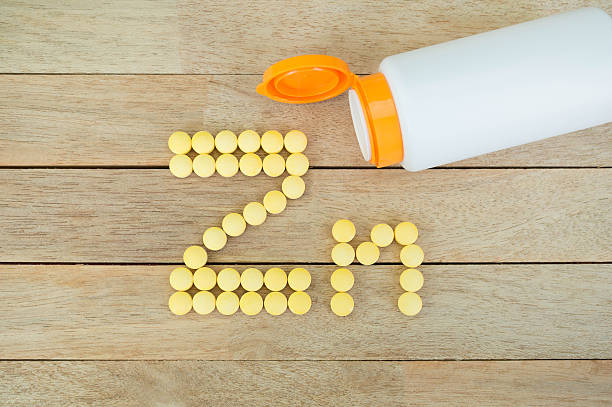 Yellow pills forming shape to Zn alphabet on wood background Yellow pills forming shape to Zn alphabet on wood background zinc stock pictures, royalty-free photos & images