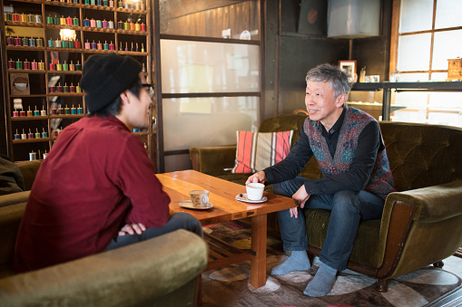 Father and son sat talking over coffee and smiling. Okayama, Japan. March 2016
