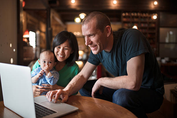famiglia che guarda un computer insieme - sucking asian ethnicity baby mother foto e immagini stock