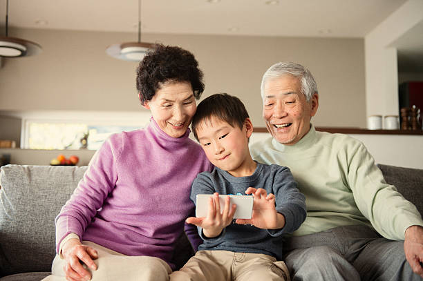 Grandson taking a family photo with smartphone Multi-generation Family taking a family photo with smartphone osaka prefecture photos stock pictures, royalty-free photos & images