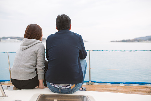 Mature couple on a luxury yacht looking out to sea. Okayama, Japan. March 2016