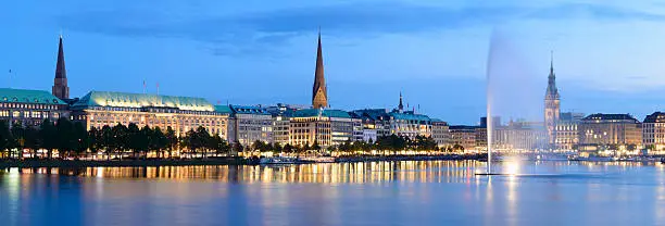 Panoramic view of the Hamburg city skyline viewed across Alster Lake at twilight, Germany.