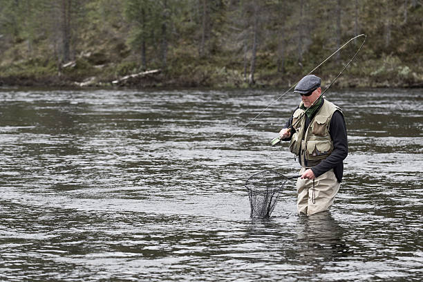 istock Fly fisherman grey cap sunglasses vest catching fish 515518745