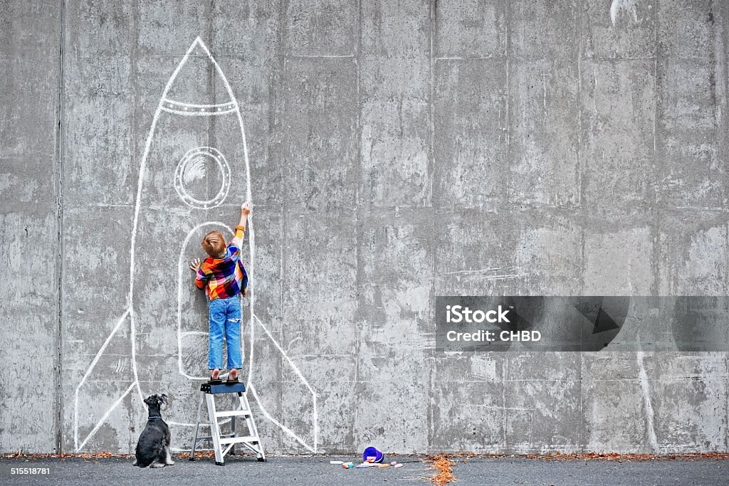 Dream Big Little boy drawing a huge rocket on the wall. Child Stock Photo