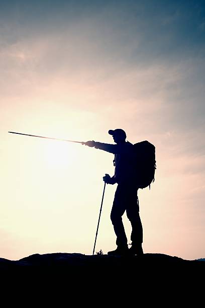 istock Tourist guide with heavy backpack show right way with pole 515518830