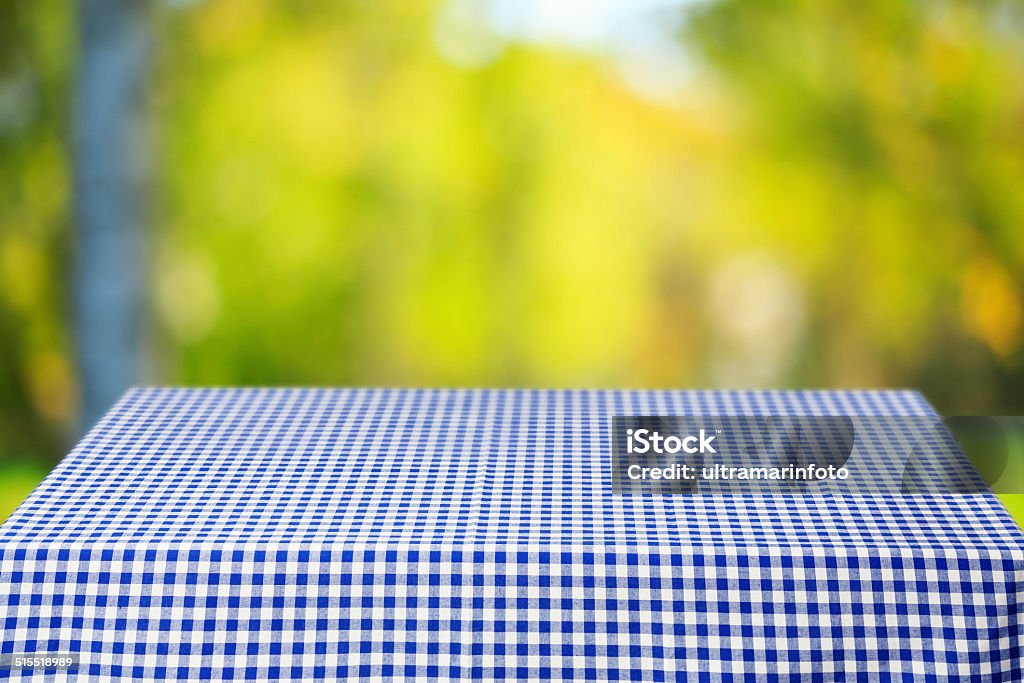 Picnic table Picnic table, covered with a checkered tablecloth. Ideal to position products on and place in the foreground of any image.  Selective focus. Very shallow depth of field for soft background. Tablecloth Stock Photo