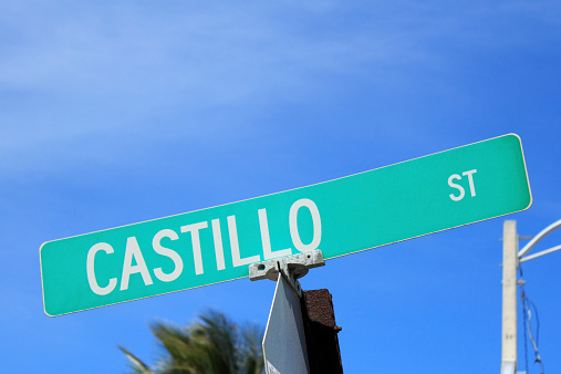 Closeup of a green and white public Castillo Street sign with a sunny blue sky background in Fort Lauderdale, Florida..