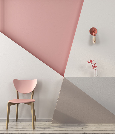 Pink chair on the background of a wall with geometric shapes in pink and gray colors