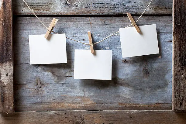 Blank photos hanging from a rope on a wooden background.