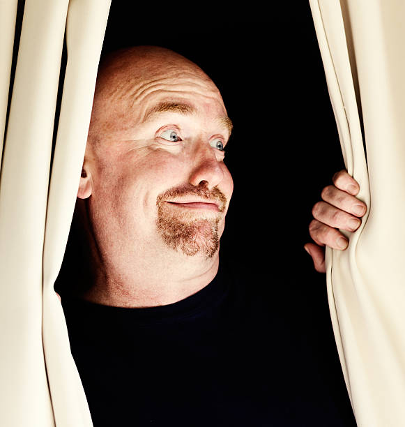 istock Get a load of that! Smiling man peeping through curtains 515521461