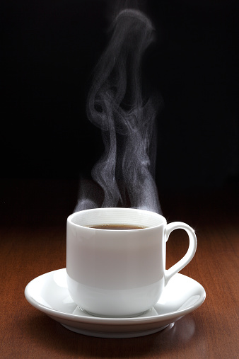 Cup of black coffee with steam on the wooden table