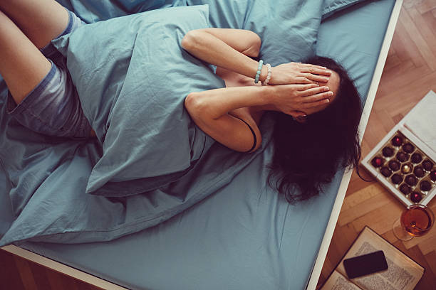 Girl crying in bed Depressed woman in bed with hands on face headache menstruation pain cramp stock pictures, royalty-free photos & images