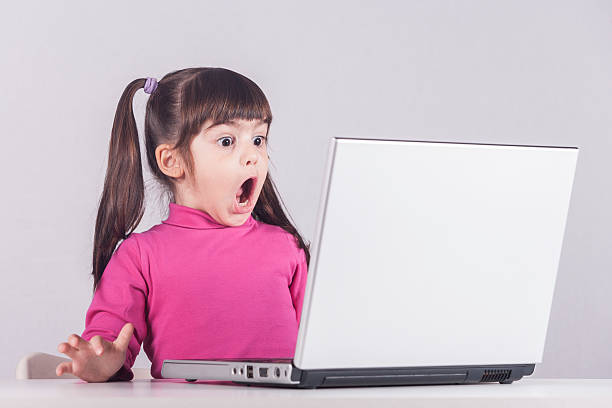 Little girl reacts while using a laptop Little girl reacts while using a laptop. Internet safety concept. Toned image with selective focus Pigtails stock pictures, royalty-free photos & images